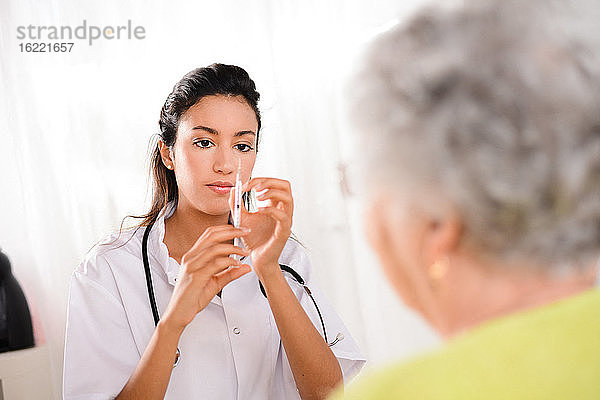 Fröhliche junge Krankenschwester gibt einer älteren Frau zu Hause eine Spritze