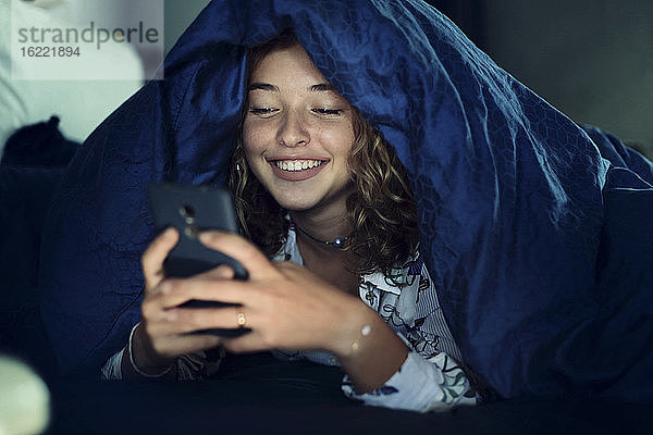 Mädchen im Teenageralter und Alltag. Im Bett mit Smartphone