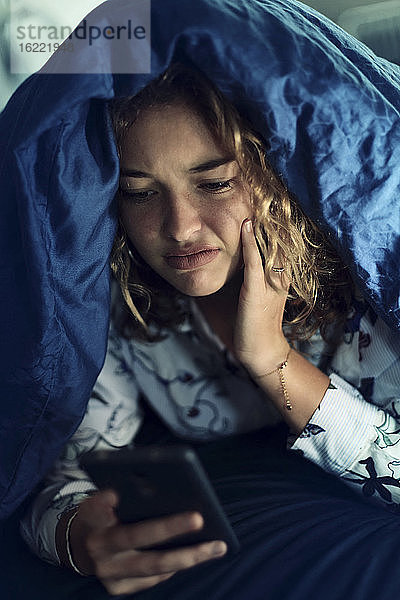 Mädchen im Teenageralter und Alltag. Im Bett mit Smartphone