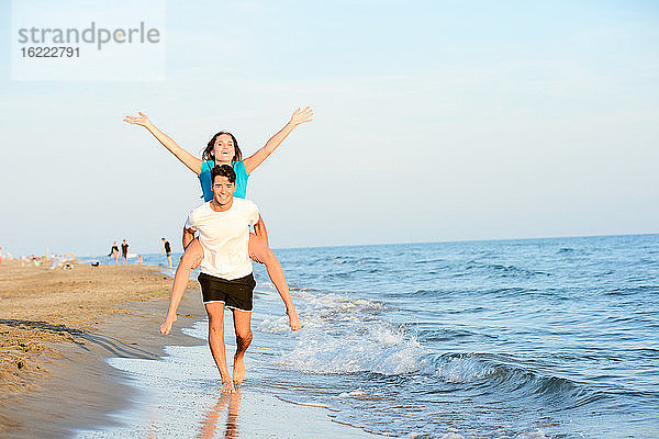 Romantisches junges Paar geht barfuß zusammen im Sand am Strand des Mittelmeers bei Sonnenuntergang