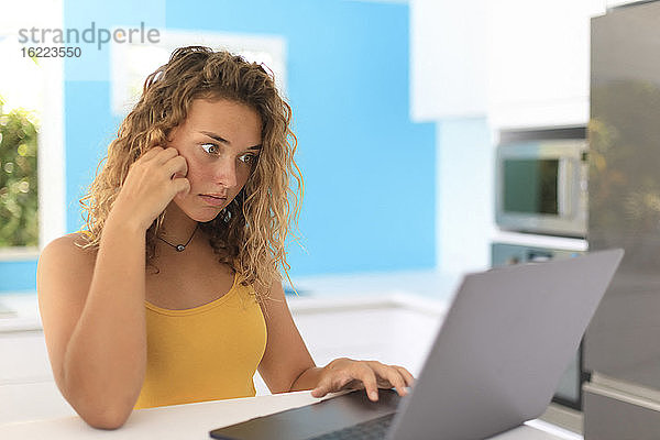 Junge Frau in ihrer Wohnung vor einem Laptop sitzend. Akquise