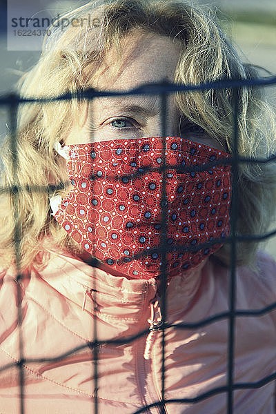 Blonde Frau mit einer alternativen Maske hinter einem Gitter