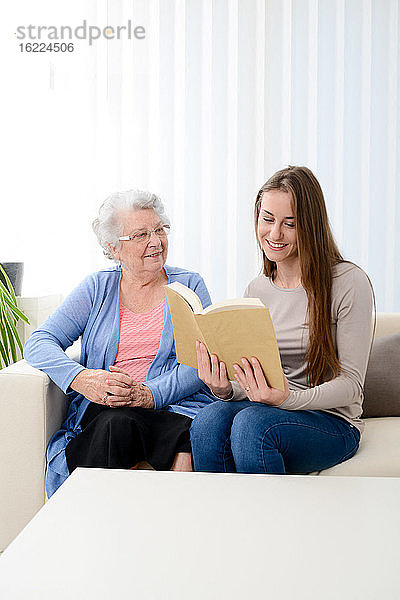 Fröhliche junge Frau hilft einer älteren Frau zu Hause mit dem Laptop