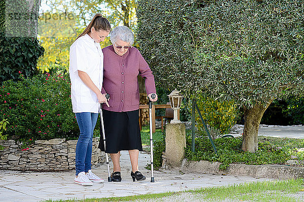 Ältere ältere Frau mit einer Krankenschwester zu Fuß im Freien in Pflegeheim Krankenhaus Garten