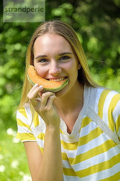 Porträt junge blonde Frau  beißt in eine Melone  Obst  Sommer  Bayern  Deutschland  Europa