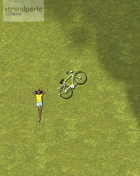 Draufsicht auf ein Mädchen  das sich auf einer Wiese neben einem Fahrrad sonnt