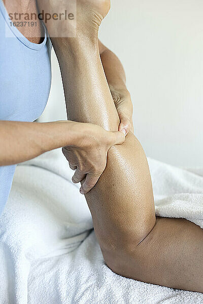 Massagetherapeutin bei der Arbeit am Bein eines Patienten