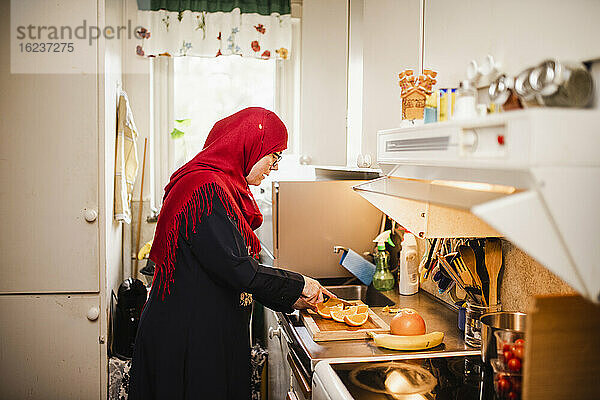 Frau in Küche schneidet Orangen