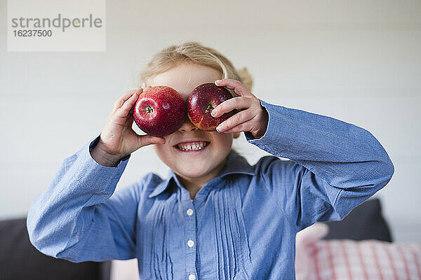 Mädchen hält Äpfel über die Augen