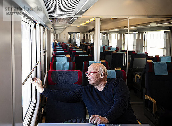 Älterer Mann schaut durch das Zugfenster