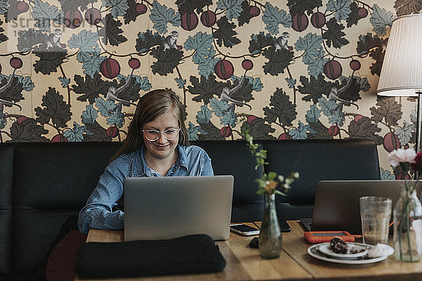Lächelnde Frau mit Laptop in einem Café
