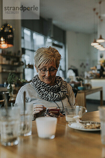 Ältere Frau telefoniert im Cafe