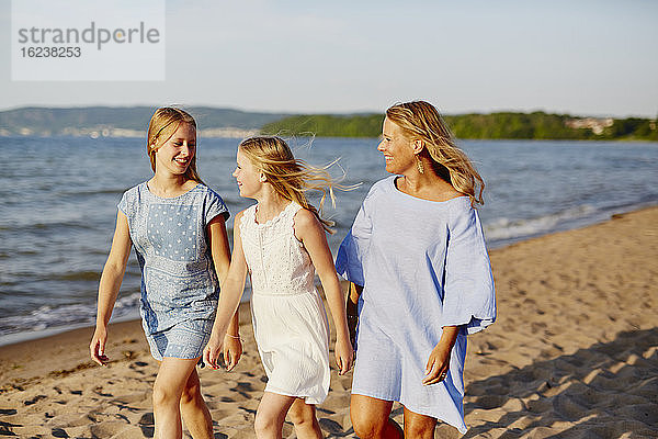 Mutter mit Töchtern spazieren am Strand