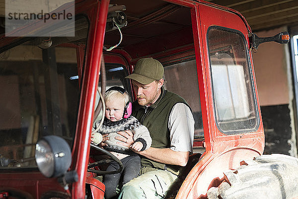 Mann mit Kleinkind im Traktor