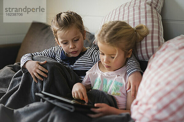 Schwestern mit digitalem Tablet auf dem Sofa