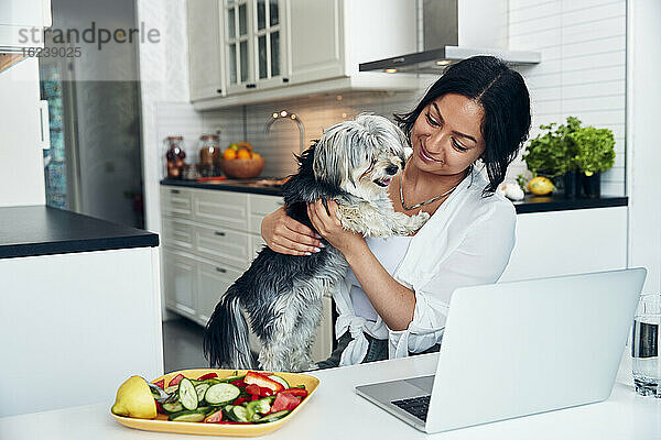 Lächelnde Frau in der Küche mit Hund