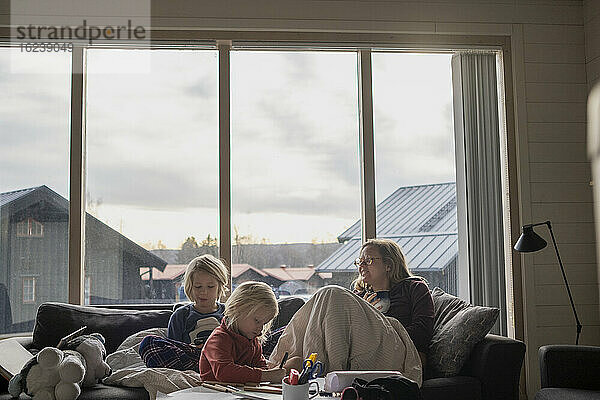 Mutter sitzt mit Töchtern auf dem Sofa