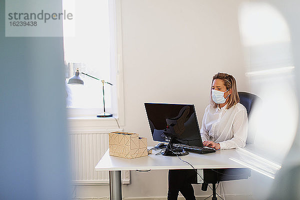 Frau im Büro mit Schutzmaske