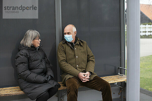 Altes Paar wartet mit Gesichtsmaske auf den Bus