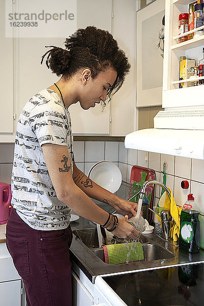 Mann wäscht Geschirr in der Küche