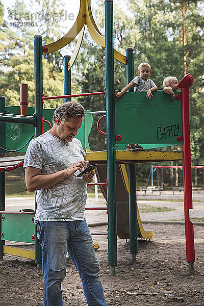 Vater mit Kindern auf dem Spielplatz