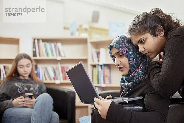 Teenager-Mädchen sitzen zusammen in der Bibliothek