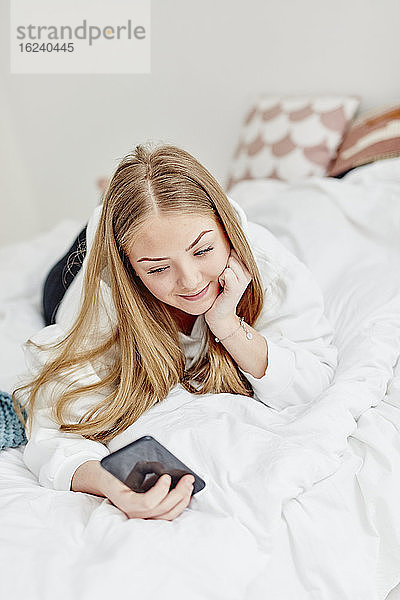 Frau im Bett mit Mobiltelefon