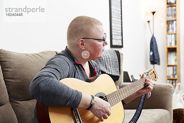 Gitarre spielende Frau auf Sofa