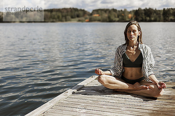Frau meditiert auf Steg