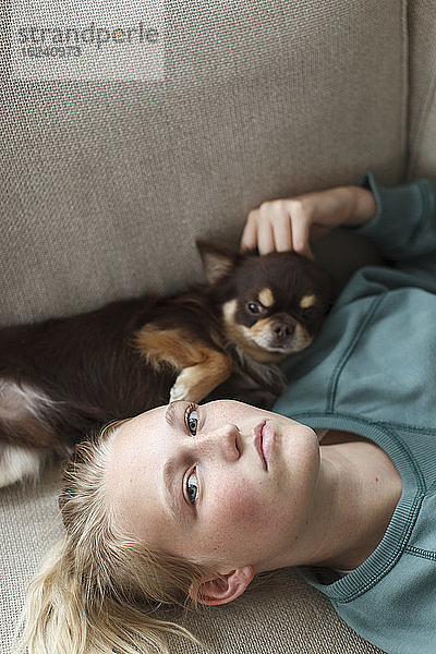 Teenager-Mädchen auf dem Bett liegend mit Hund