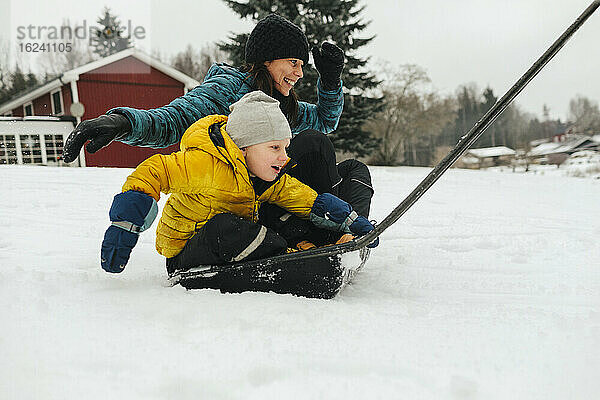 Mutter mit Sohn auf Schlitten Schneeschaufel