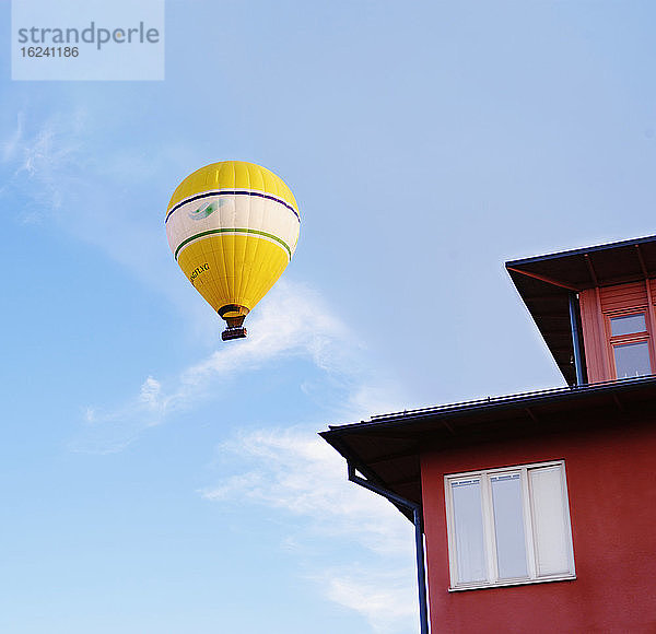 Heißluftballon fliegt über ein rotes Haus