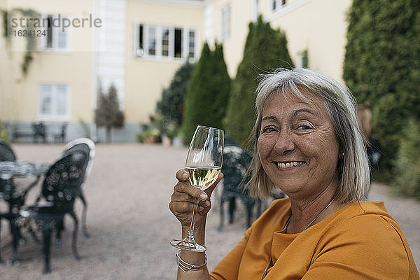 Lächelnde Frau hält ein Glas Wein