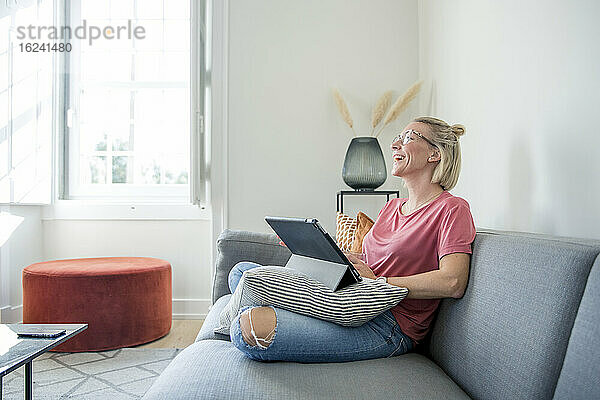Frau auf Sofa mit digitalem Tablet
