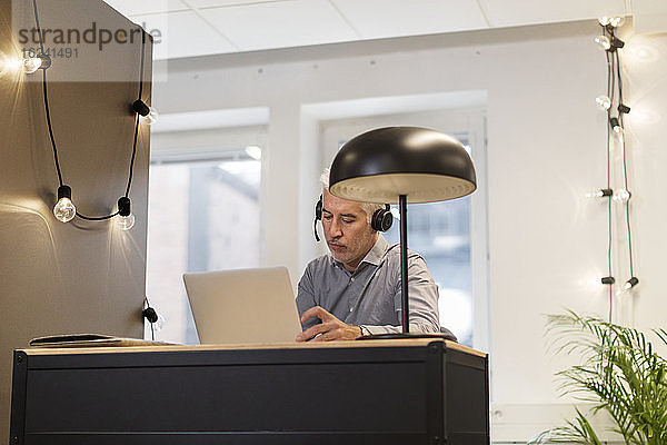 Mann mit Headset bei der Arbeit im Büro