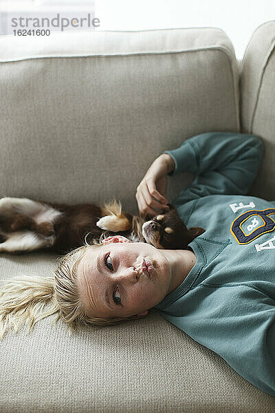 Teenager-Mädchen auf dem Bett liegend mit Hund