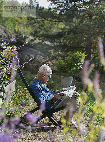 Mann im Garten liest Zeitung