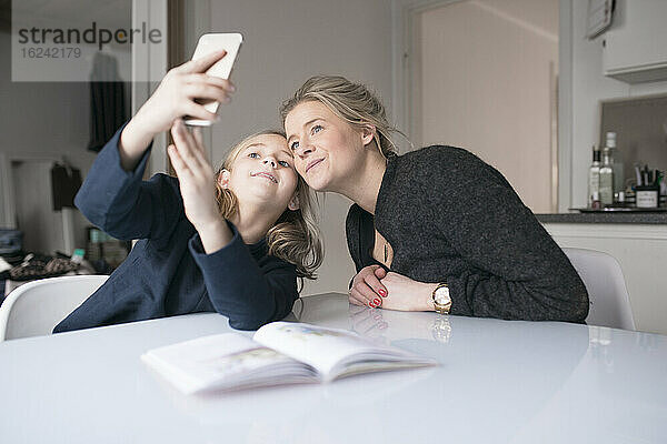 Mutter und Tochter machen Selfie bei den Hausaufgaben