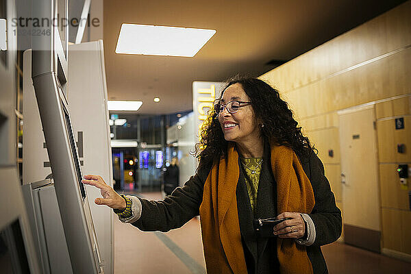 Frau kauft Fahrkarten am Fahrkartenautomaten
