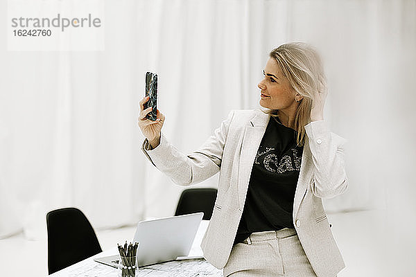 Geschäftsfrau am Schreibtisch nimmt Selfie