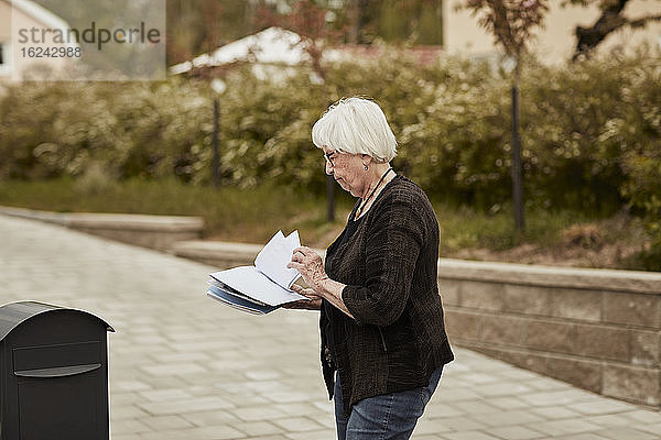 Ältere Frau steht in der Nähe des Briefkastens