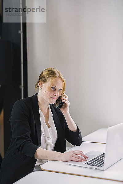 Frau im Büro  die über ein Mobiltelefon spricht