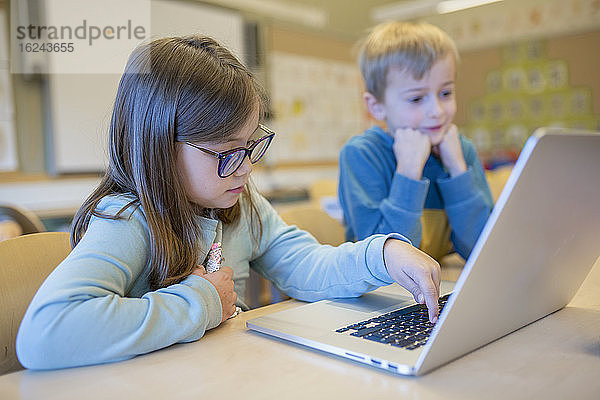 Mädchen benutzt Laptop im Klassenzimmer