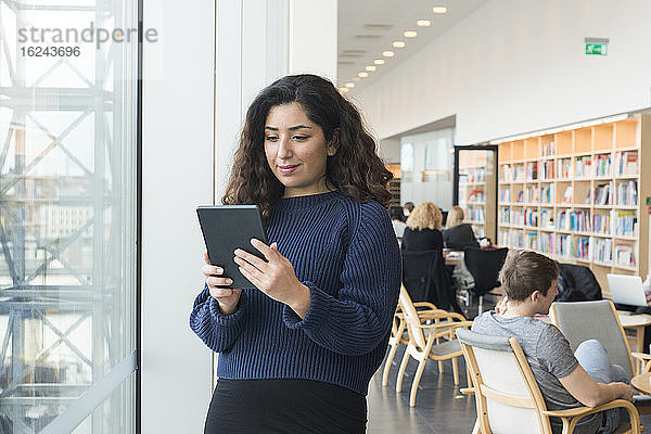 Frau benutzt digitales Tablet in der Bibliothek