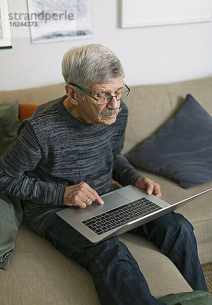 Älterer Mann mit Laptop auf dem Sofa