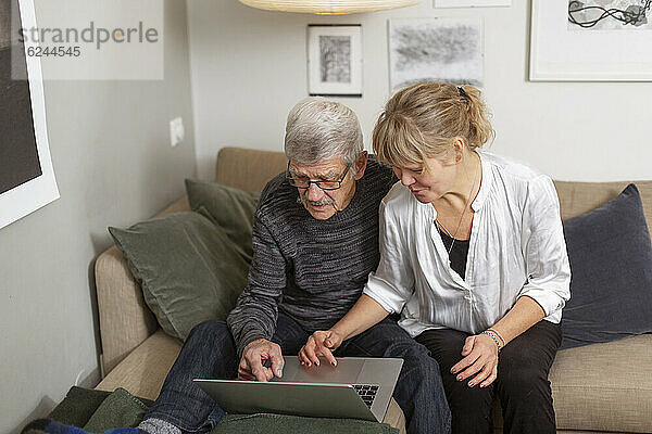 Ehepaar benutzt Laptop auf Sofa