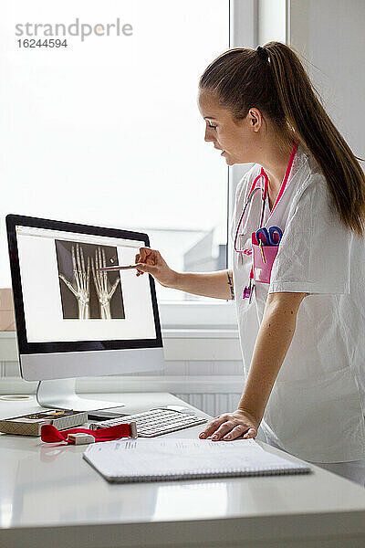 Ärztin im Büro zeigt auf Röntgenbild