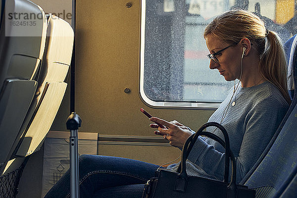Frau im Zug mit Mobiltelefon