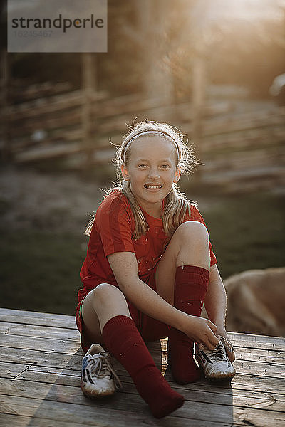 Lächelndes Mädchen zieht Fußballschuhe an