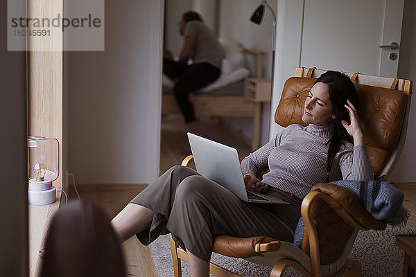 Frau auf Sessel sitzend mit Laptop